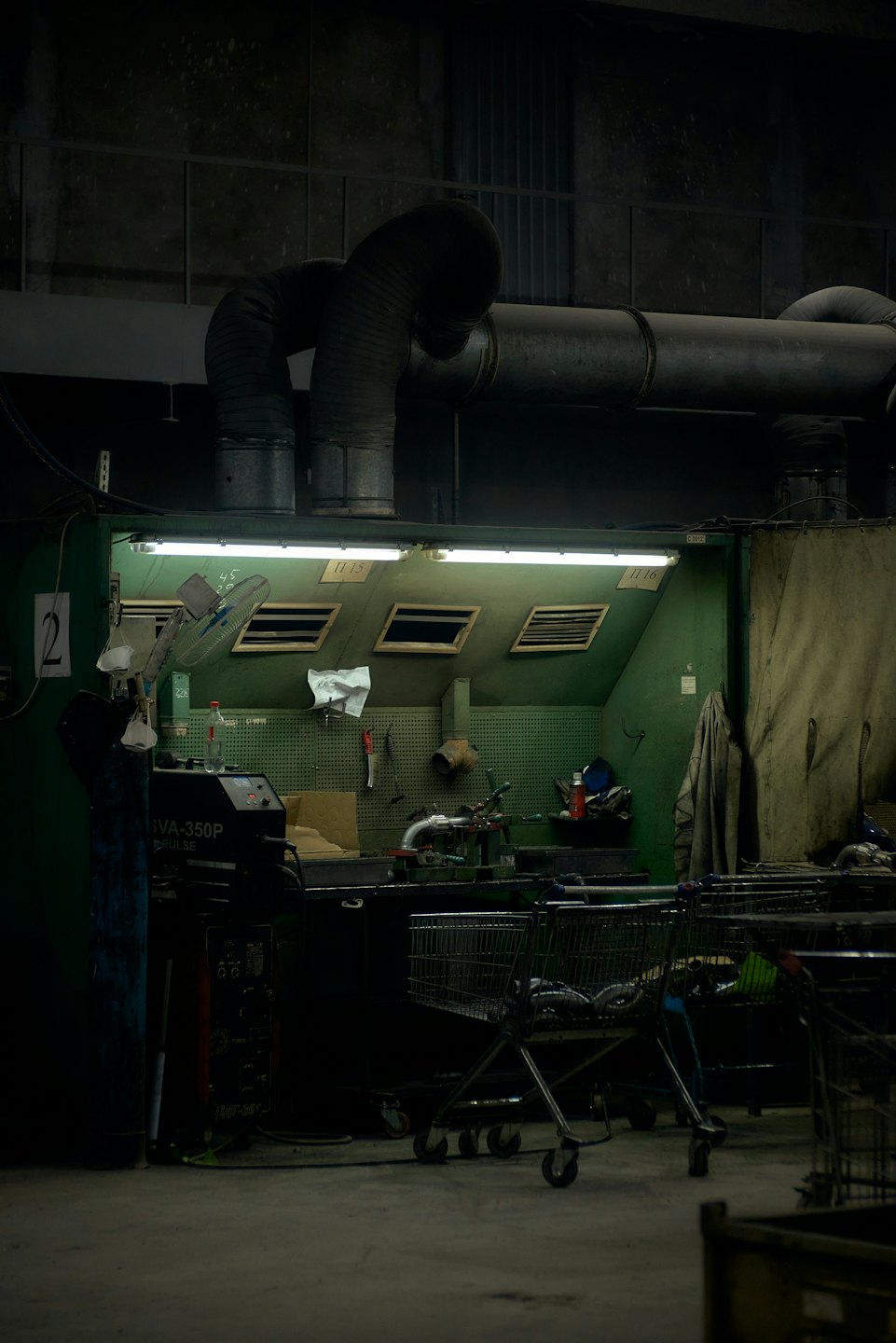 Green workbench with tools and a welding machine in a workshop.